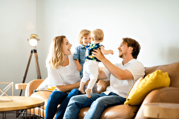 Happy parents playing with baby on the couch in a clean home