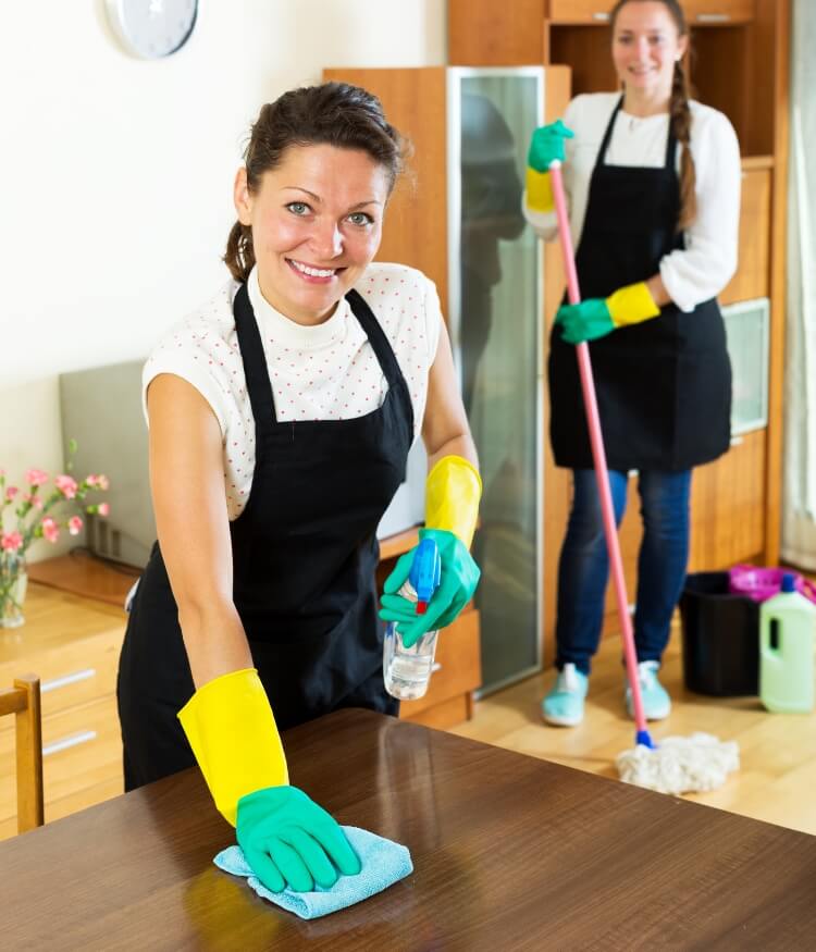 Cleaner smiling while wiping the table